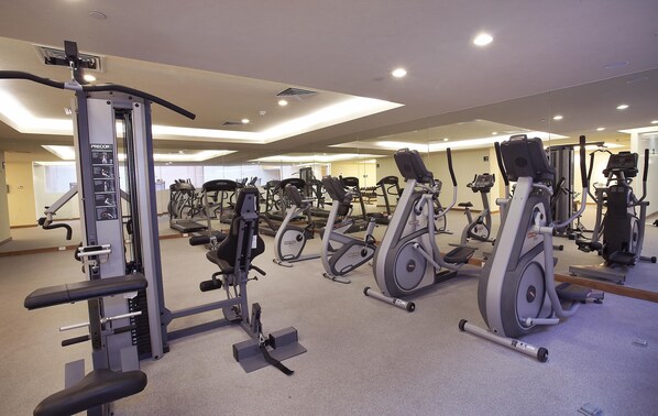 A gym with various exercise equipment, including treadmills, stationary bikes, and weight machines.