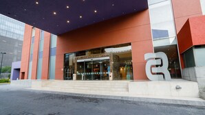 A modern building with a glass entrance, a large 'R' logo, and a red and orange facade.