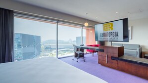 A hotel room with a large bed, a desk, a chair, and a TV mounted on the wall.