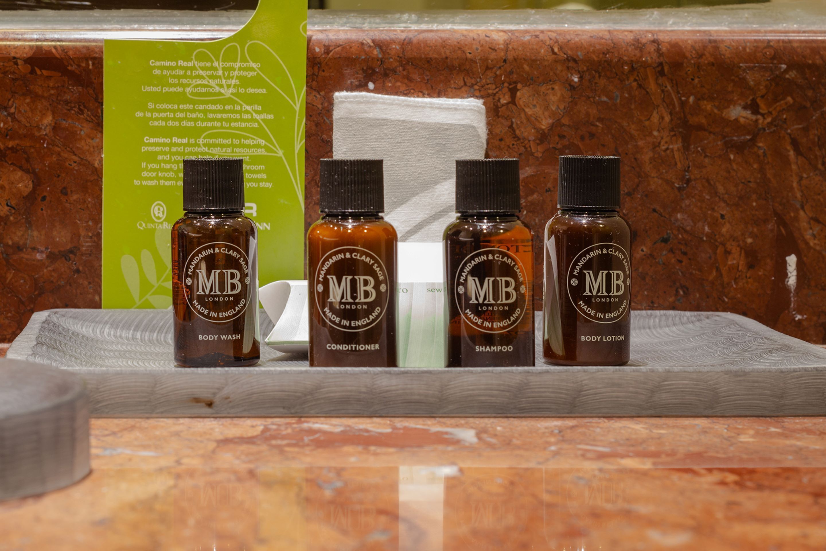 Cuatro botellas de jabón de cuerpo, acondicionador, champú y loción sobre una superficie de madera.