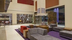 A spacious lobby with modern seating, a glass partition, and a view of the city.