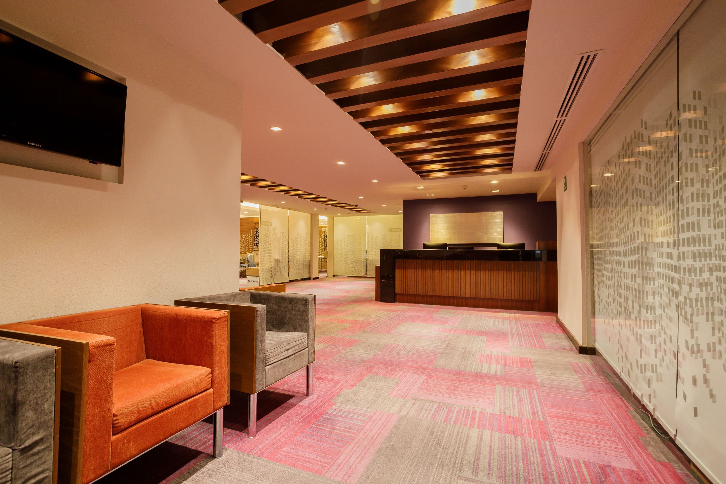 Un hall d’hôtel comprenant un comptoir d’accueil, un espace salon et un tapis à motifs.
