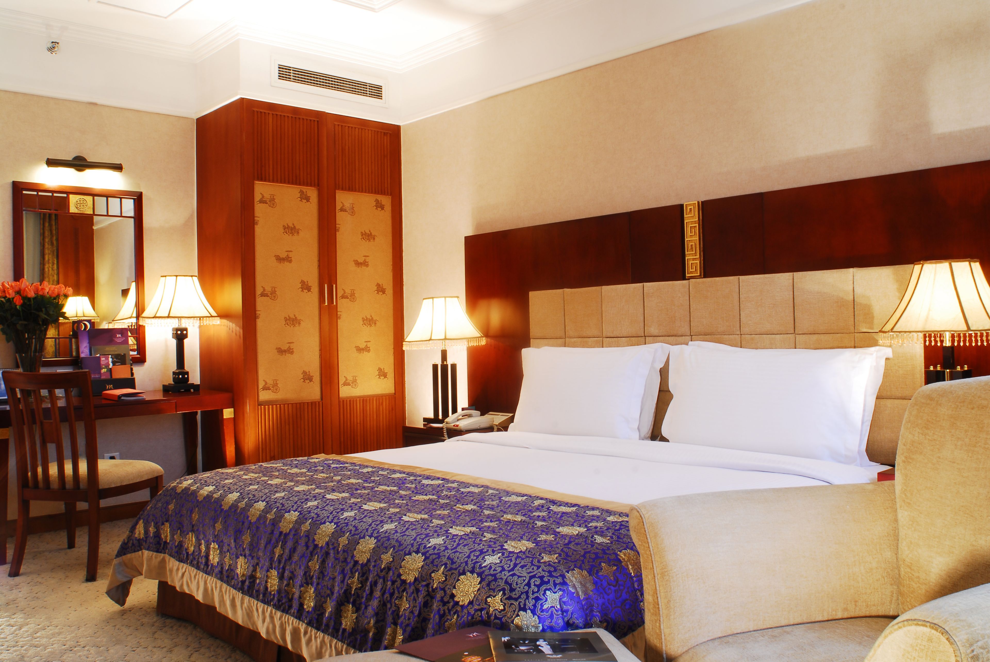 Una camera d'hotel con un letto grande, due comodini, una scrivania con una sedia e un armadio.