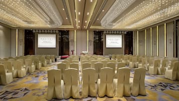 A conference room with rows of chairs, a carpeted floor, and a chandelier.