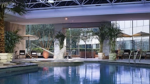An indoor swimming pool with a water feature, surrounded by lounge chairs and potted plants. - Grand Mercure Xian Renmin Square (Xi'an)