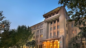 A large, historic building with a grand entrance, multiple floors, and a prominent staircase leading to the main doors. - Grand Mercure Xian Renmin Square (Xi'an)
