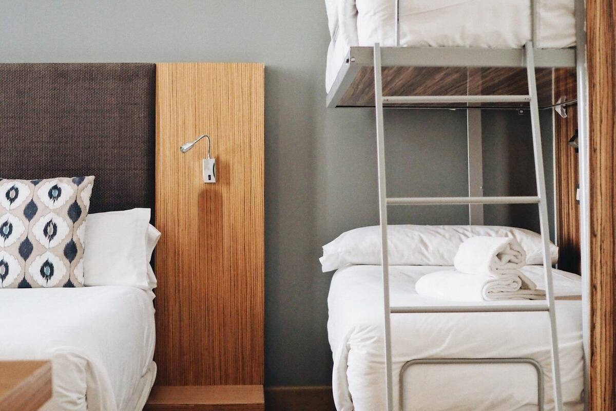 Habitación de hotel con una cama litera, un panel de pared de madera y una mesita de noche con lámpara.