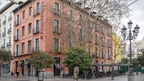 Un immeuble à plusieurs étages, doté d’une façade rose, de balcons et d’espaces de détente en plein air.