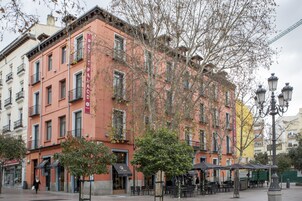 A multi-story building with a pink facade, balconies, and outdoor seating areas.