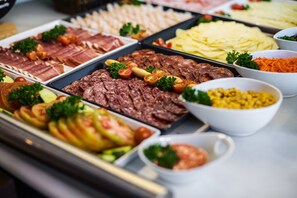 A buffet with various food items including meats, cheeses, and vegetables.