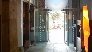 L’entrée d’un hôtel, avec une porte en verre, un mur en briques et un grand luminaire sphérique suspendu au-dessus.
