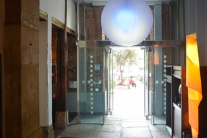 A hotel entrance with a glass door, a brick wall, and a large spherical light fixture above.