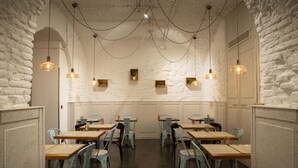 Un restaurant aux murs en briques blanches, aux tables en bois et aux chaises bleues.