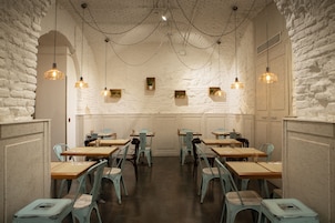 A restaurant with white brick walls, wooden tables, and blue chairs.