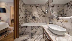 A modern bathroom with a marble wall, a freestanding bathtub, and a large sink. - Grand Hotel Union Eurostars (Ljubljana)