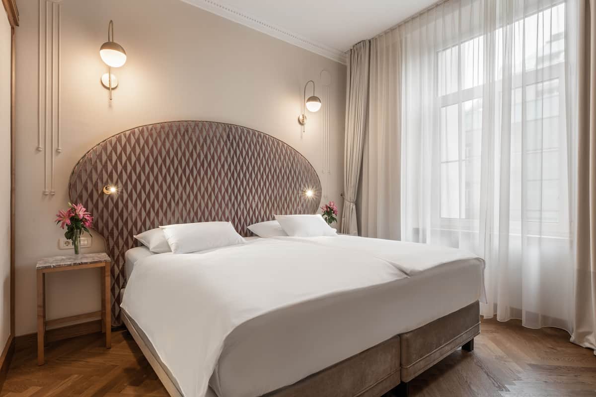 A modern bedroom with a large bed, a nightstand, and a wall-mounted light fixture.