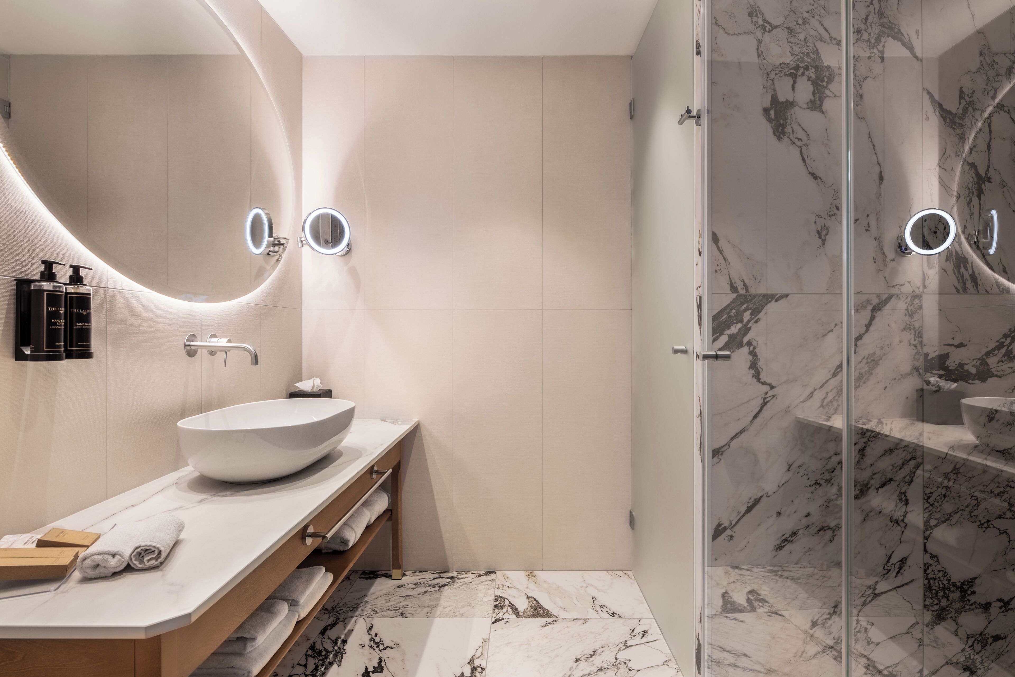 A modern bathroom with a large sink, a mirror, and a glass shower enclosure.