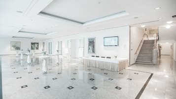 A spacious lobby with a polished marble floor, a reception desk, and a staircase leading to upper floors.
