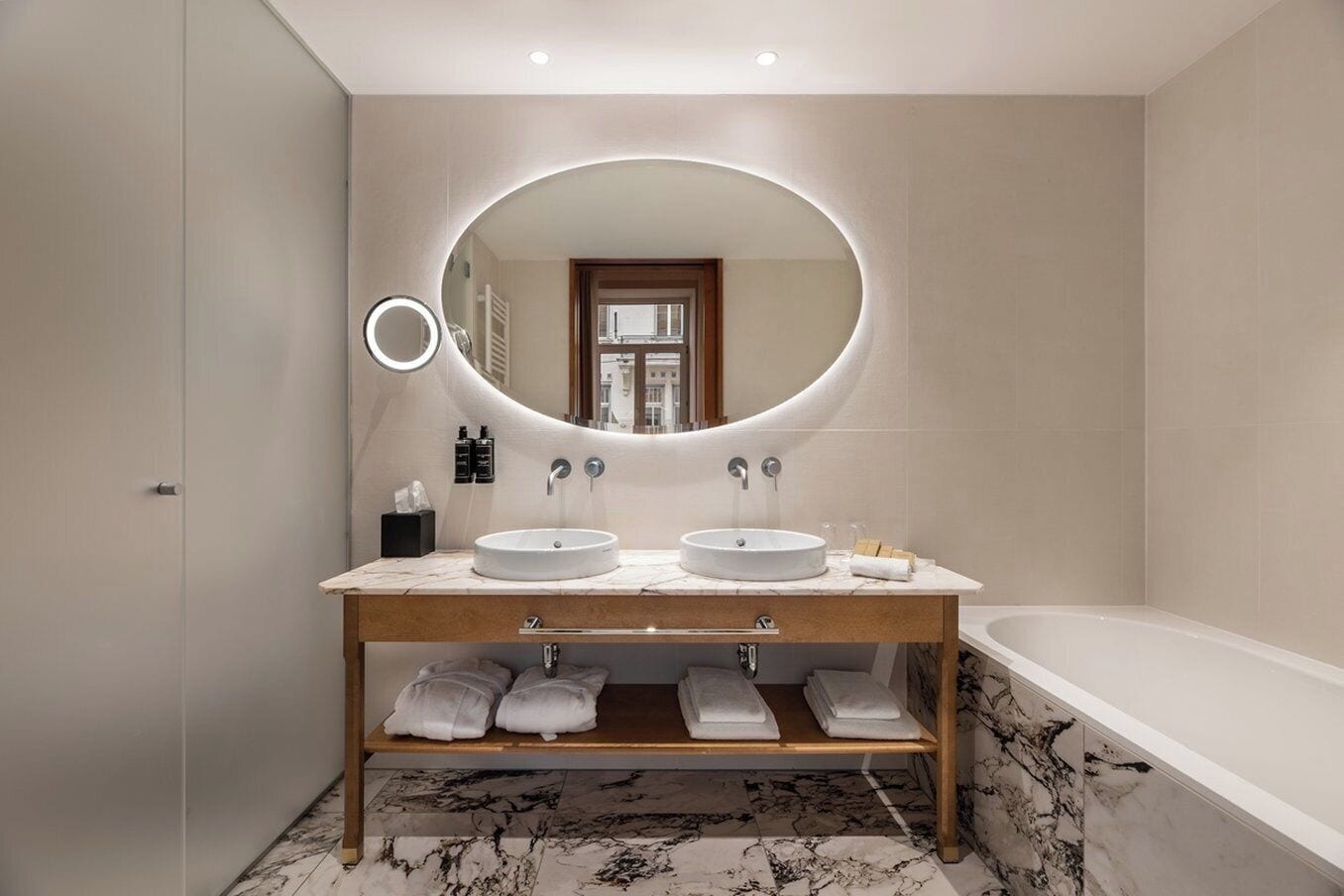 Un baño moderno con dos lavamanos, un espejo grande y una bañera.