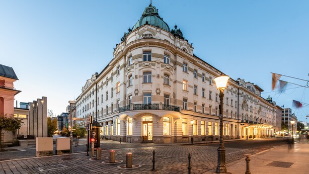 Um edifício histórico com cúpula e varanda, com várias janelas e uma entrada bem iluminada.