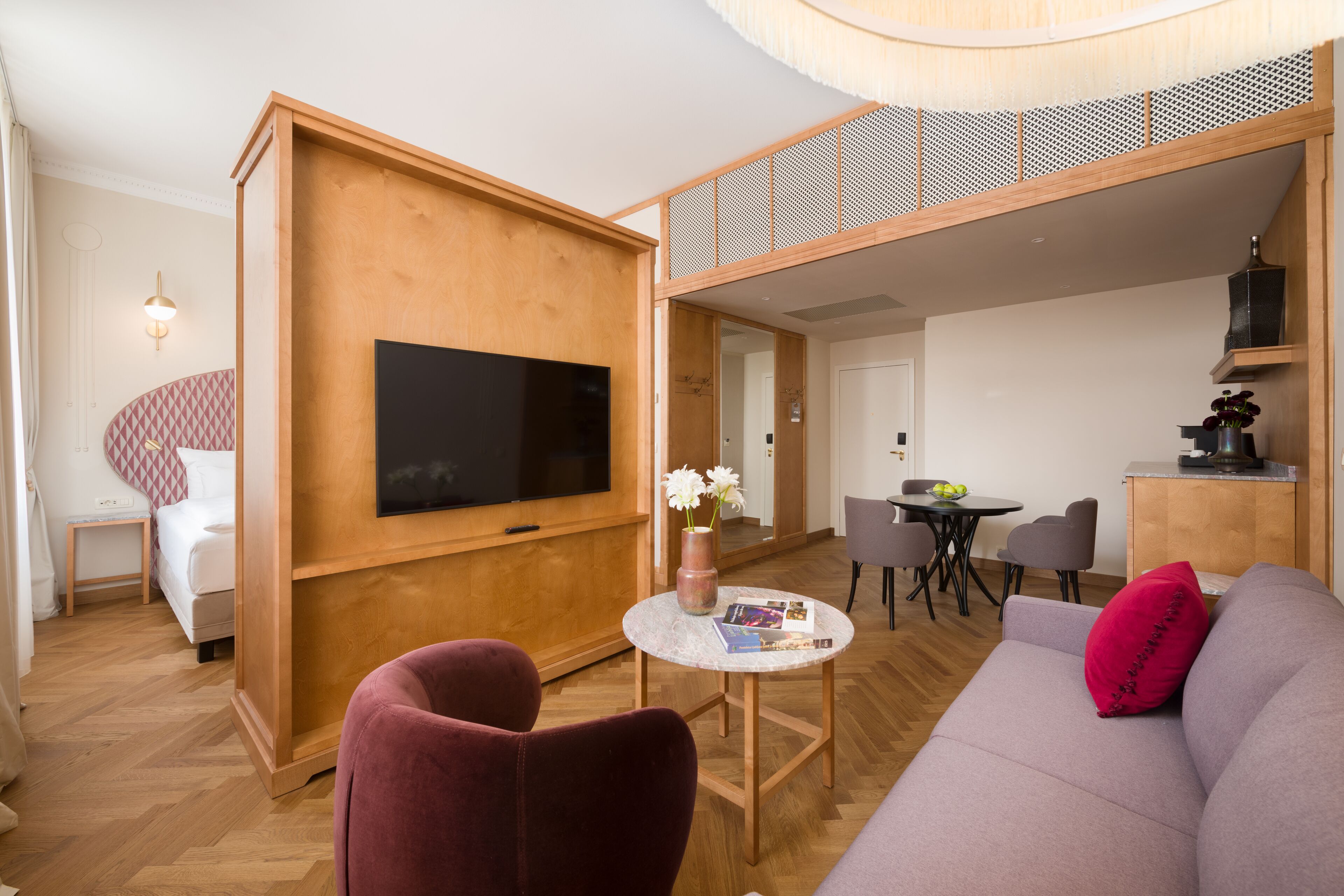 A modern living room with a flat-screen TV, a round coffee table, a sofa, and a dining area with chairs.