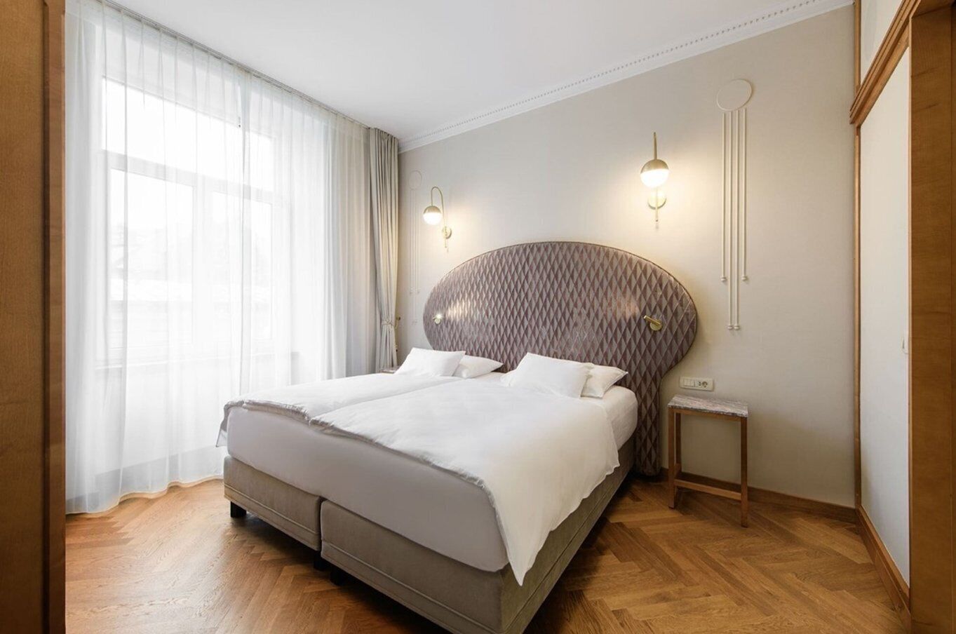 A modern hotel room with a large bed, a bedside table, and a nightstand.