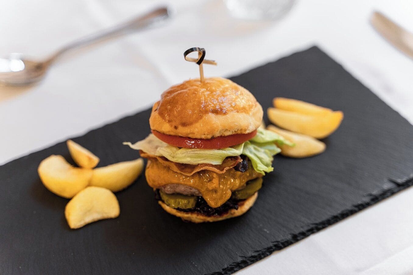 Ein Burger mit Pommes auf einer schwarzen Schieferplatte.