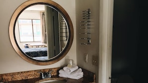 A bathroom with a granite countertop, a round mirror, a towel rack, and a toilet. - Ambassador Inn (Kissimmee)