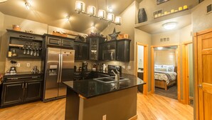 A modern kitchen with a central island, stainless steel appliances, and a hanging light fixture. - Marys Lake Lodge Mountain Resort and Condos (Estes Park)
