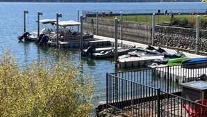 A marina with boats docked, a dock with a covered seating area, and a view of a lake with hills in the background. - Clear Lake Cottages & Marina (Clearlake)