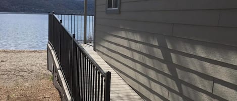Una terraza de madera con barandilla metálica que da a un lago.