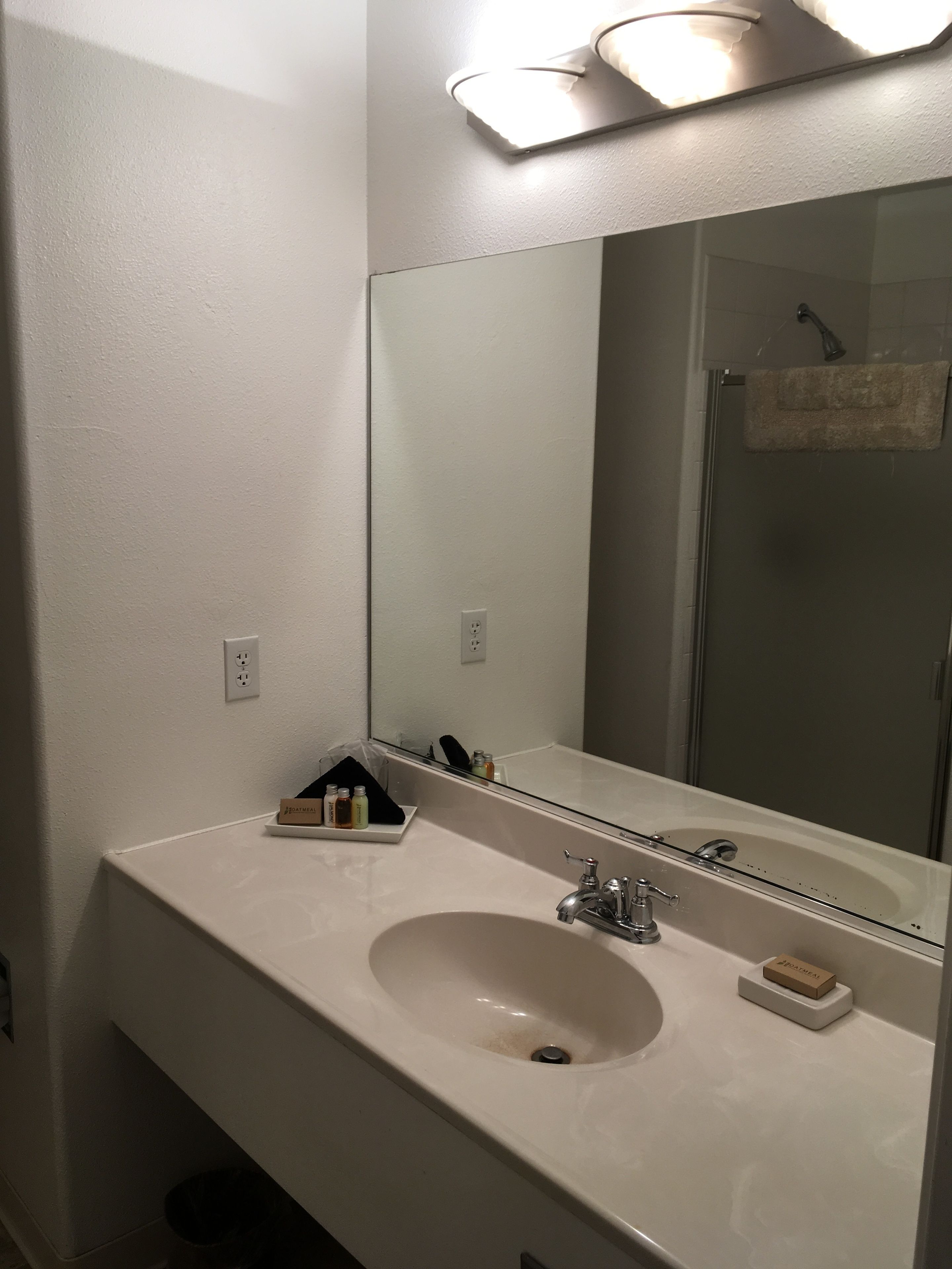 Un baño con un lavamanos blanco, un espejo y una toalla colgada en la pared.