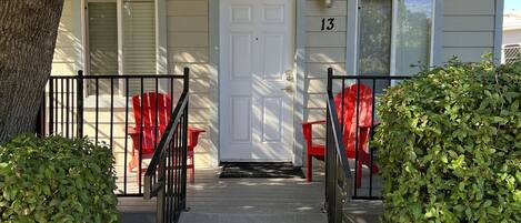 A two-story house with a front door, number 13, and two red chairs outside.