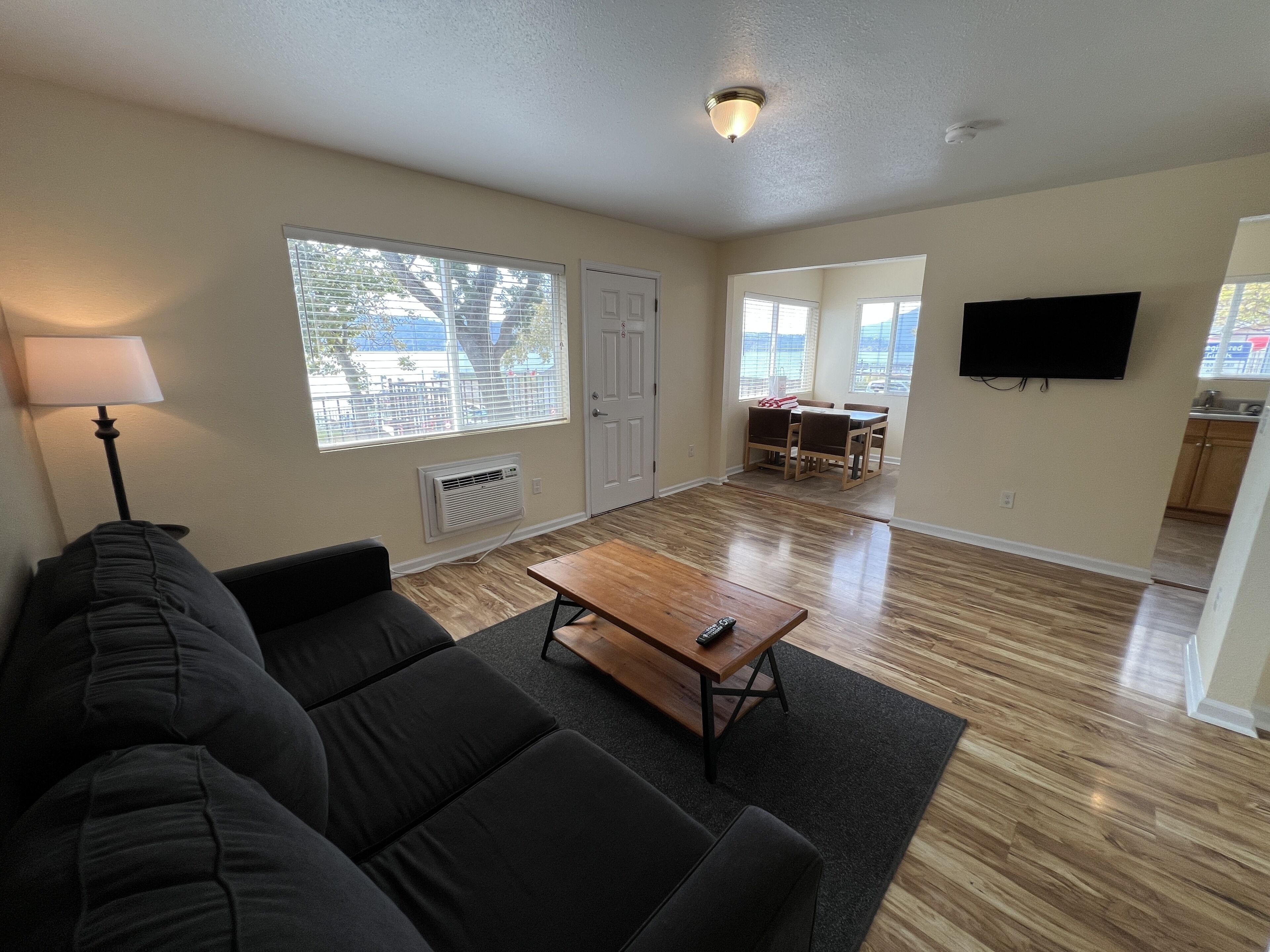 A living room with a sofa, a coffee table, and a TV. There is a dining area with a table and chairs.