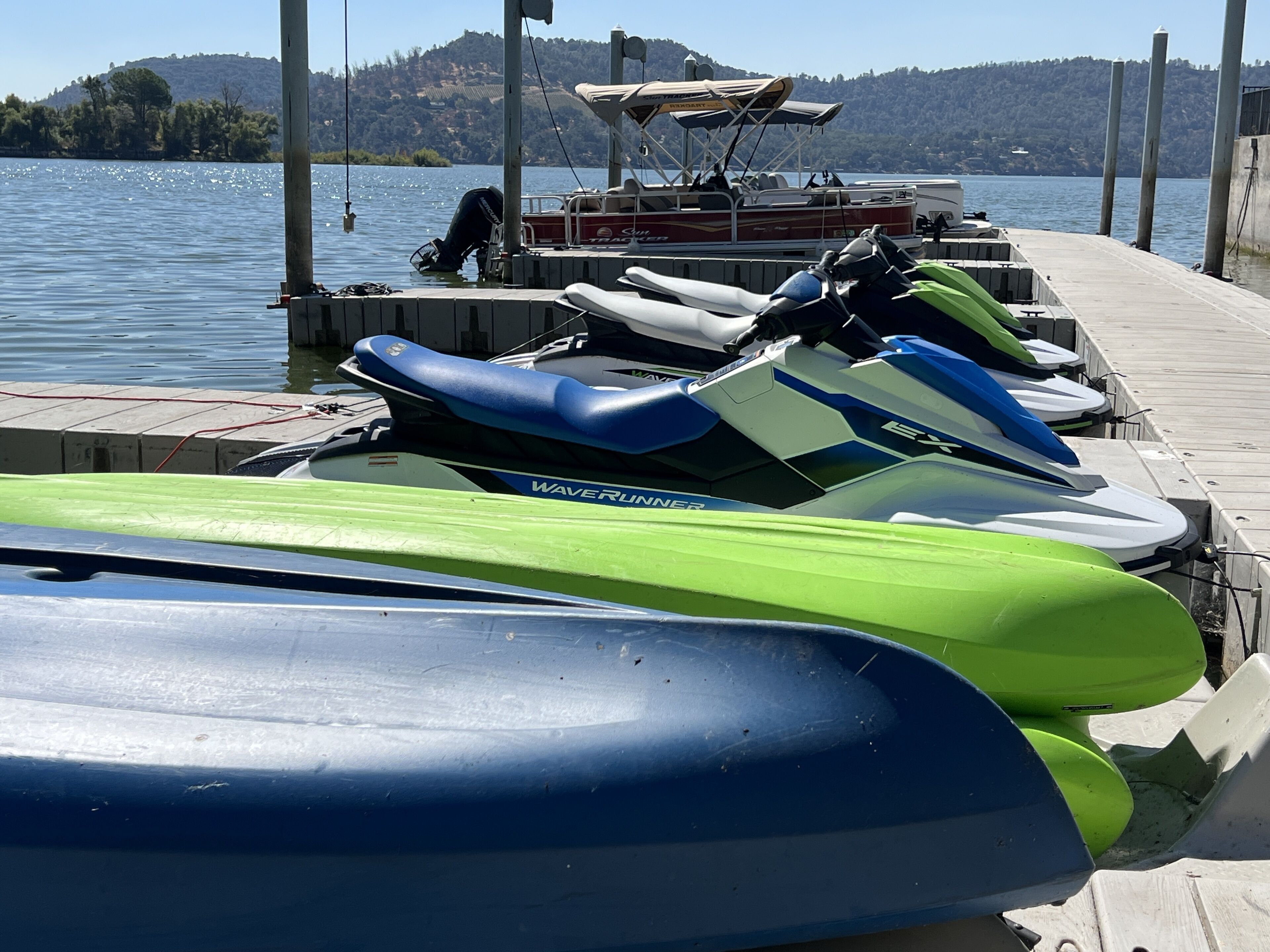 A dock with several jet skis and a boat.