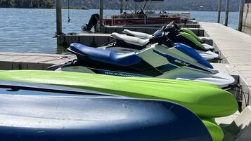 A dock with several jet skis and a boat.
