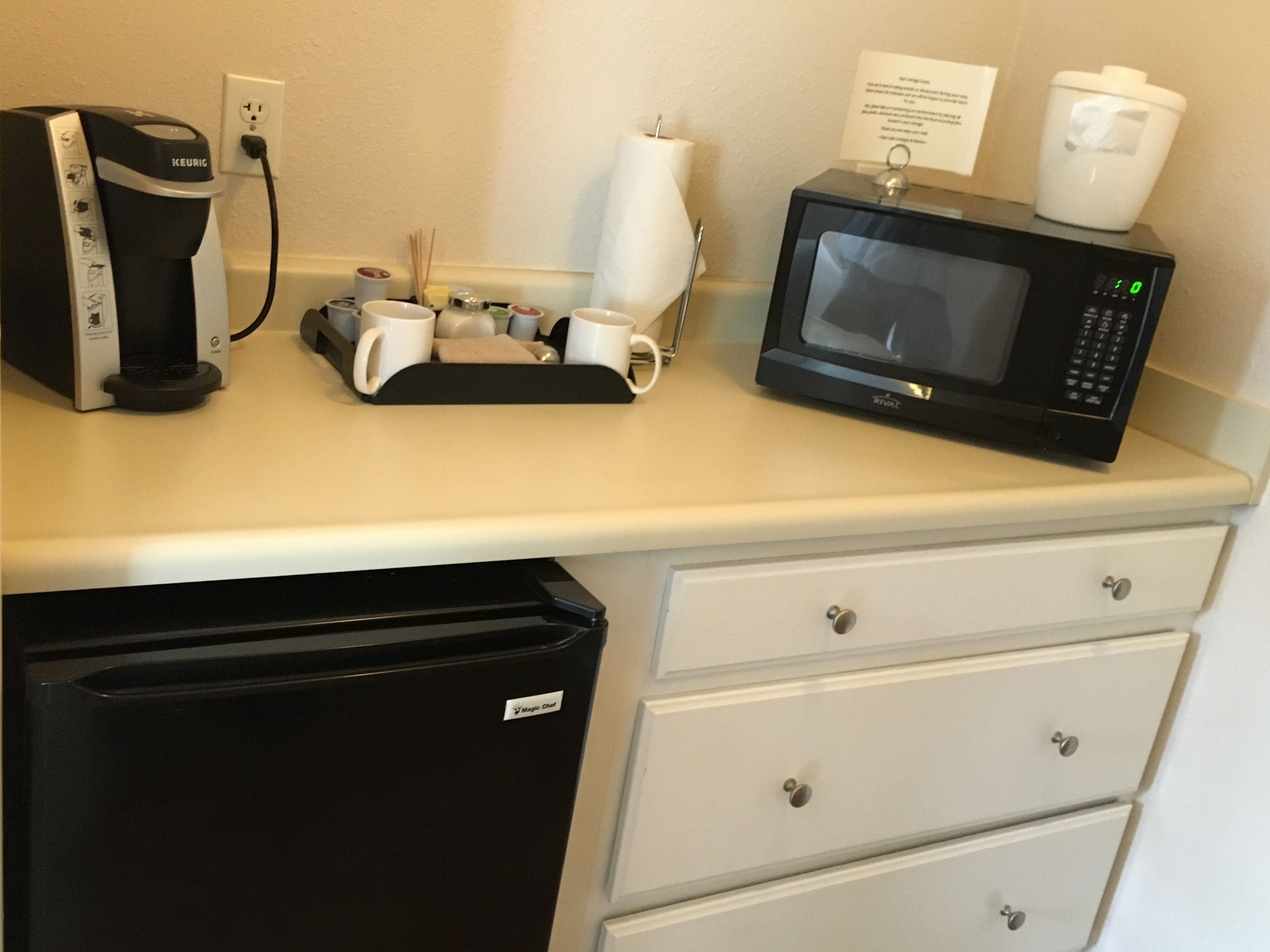 A kitchenette with a coffee maker, microwave, and a small refrigerator.