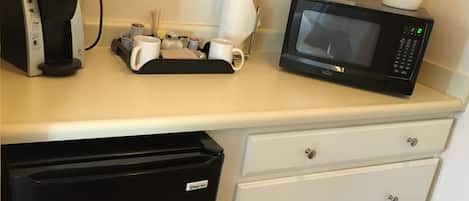 A kitchenette with a coffee maker, microwave, and a small refrigerator.