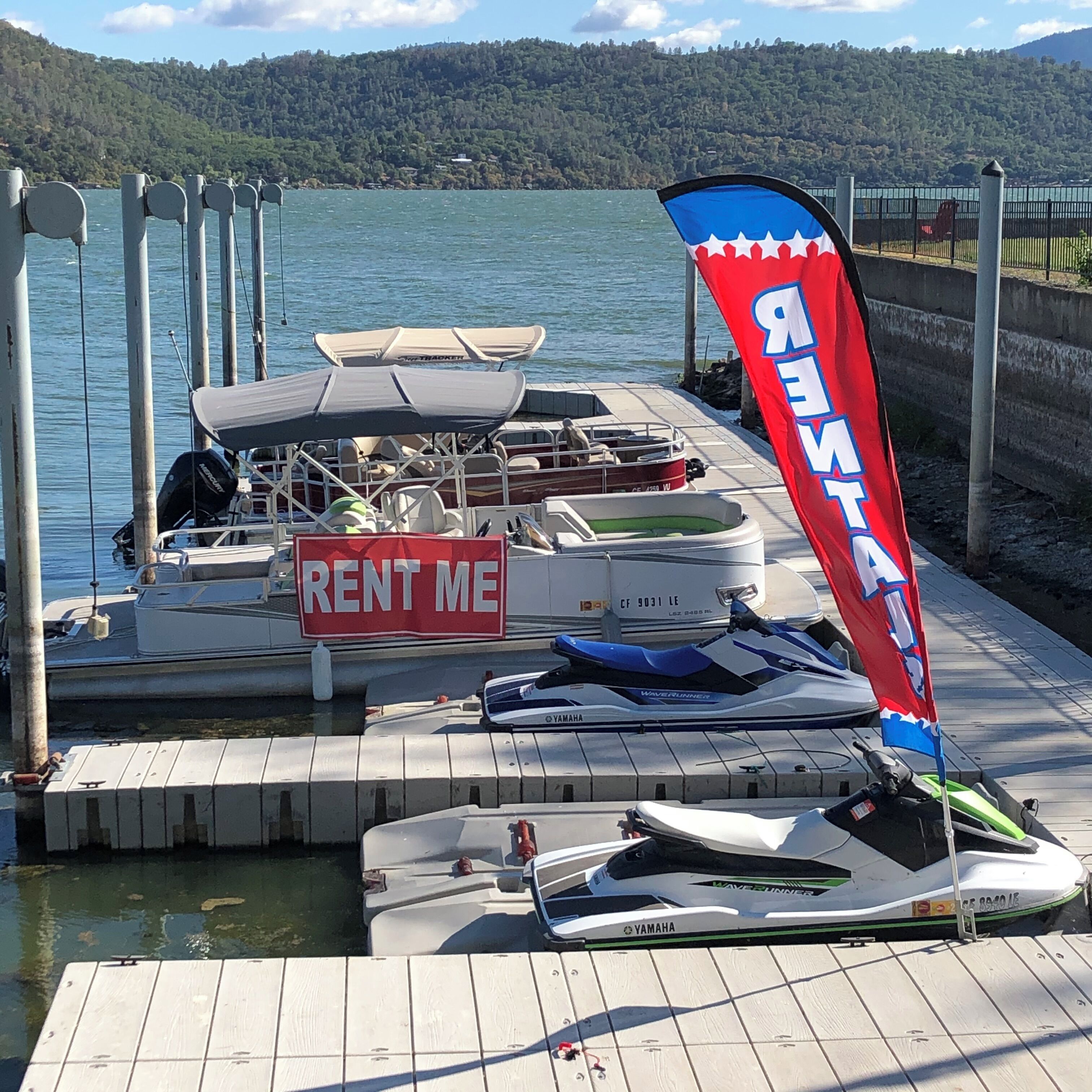 A dock with a 'RENT ME' sign, a Yamaha jet ski, and a red and blue flag.