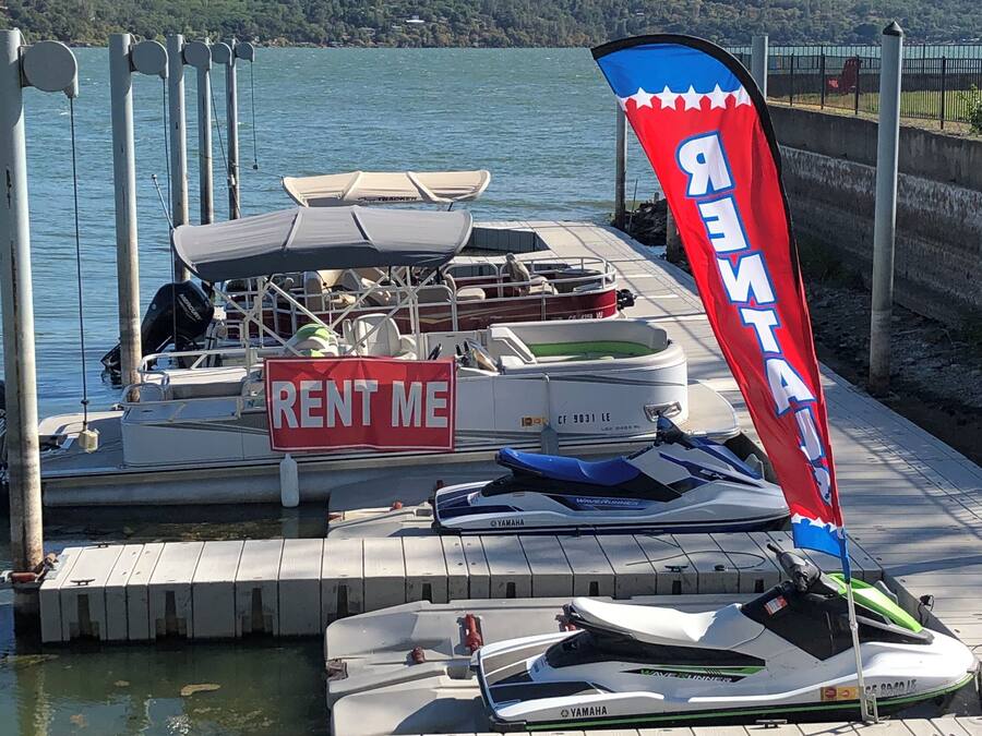 A dock with a 'RENT ME' sign, a Yamaha jet ski, and a red and blue flag.