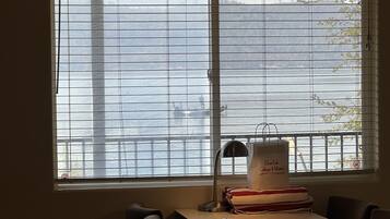 Ein Zimmer mit großem Fenster mit Blick auf ein Gewässer, einem Schreibtisch mit Lampe und einer Tasche mit dem Aufdruck 'Clear Lake Collages & Marina'.
