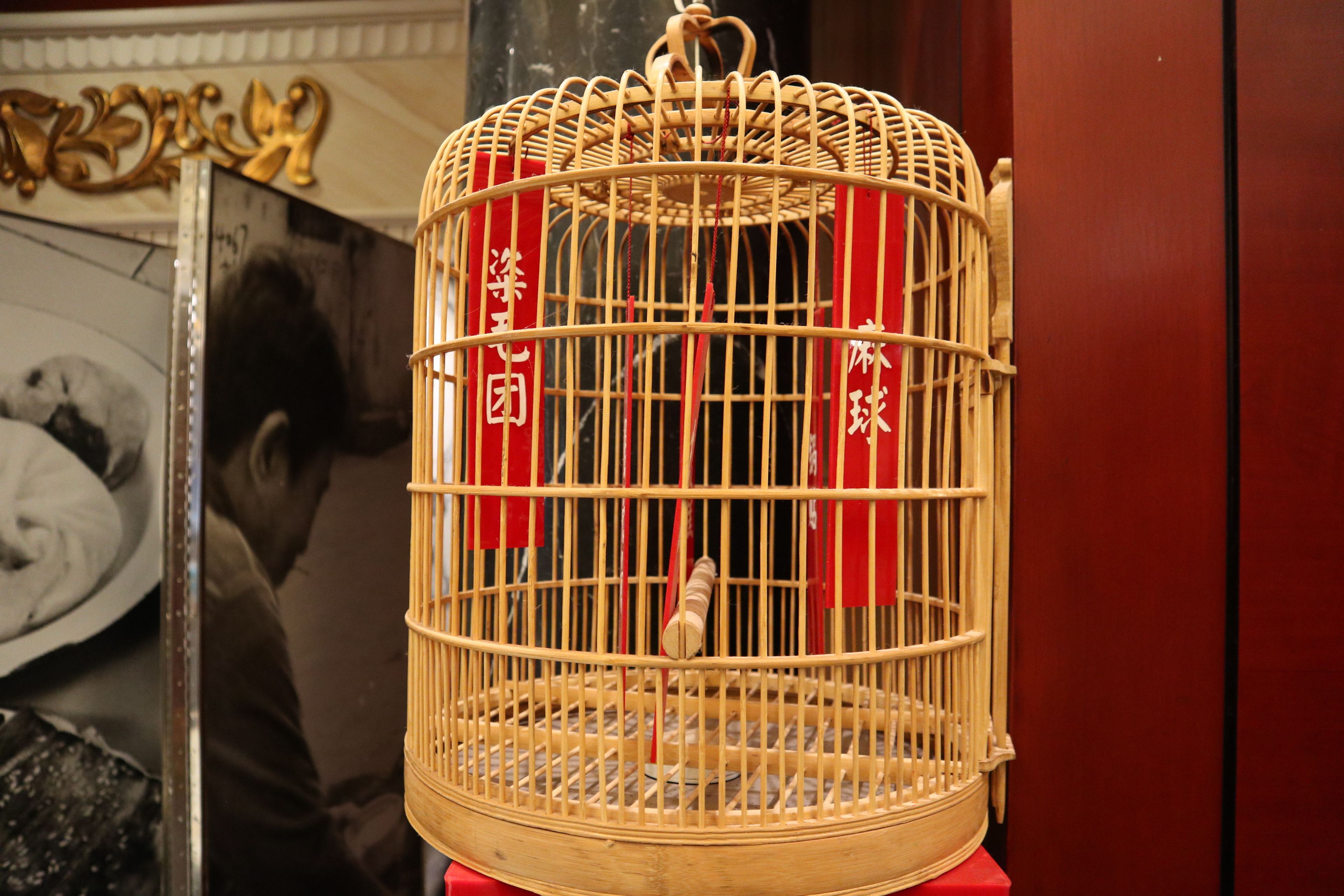 A wooden birdcage with red ribbons and Chinese characters.