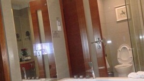 A bathroom with a large bathtub, a toilet, and a mirror. - Landscape Hotel (Fuzhou)