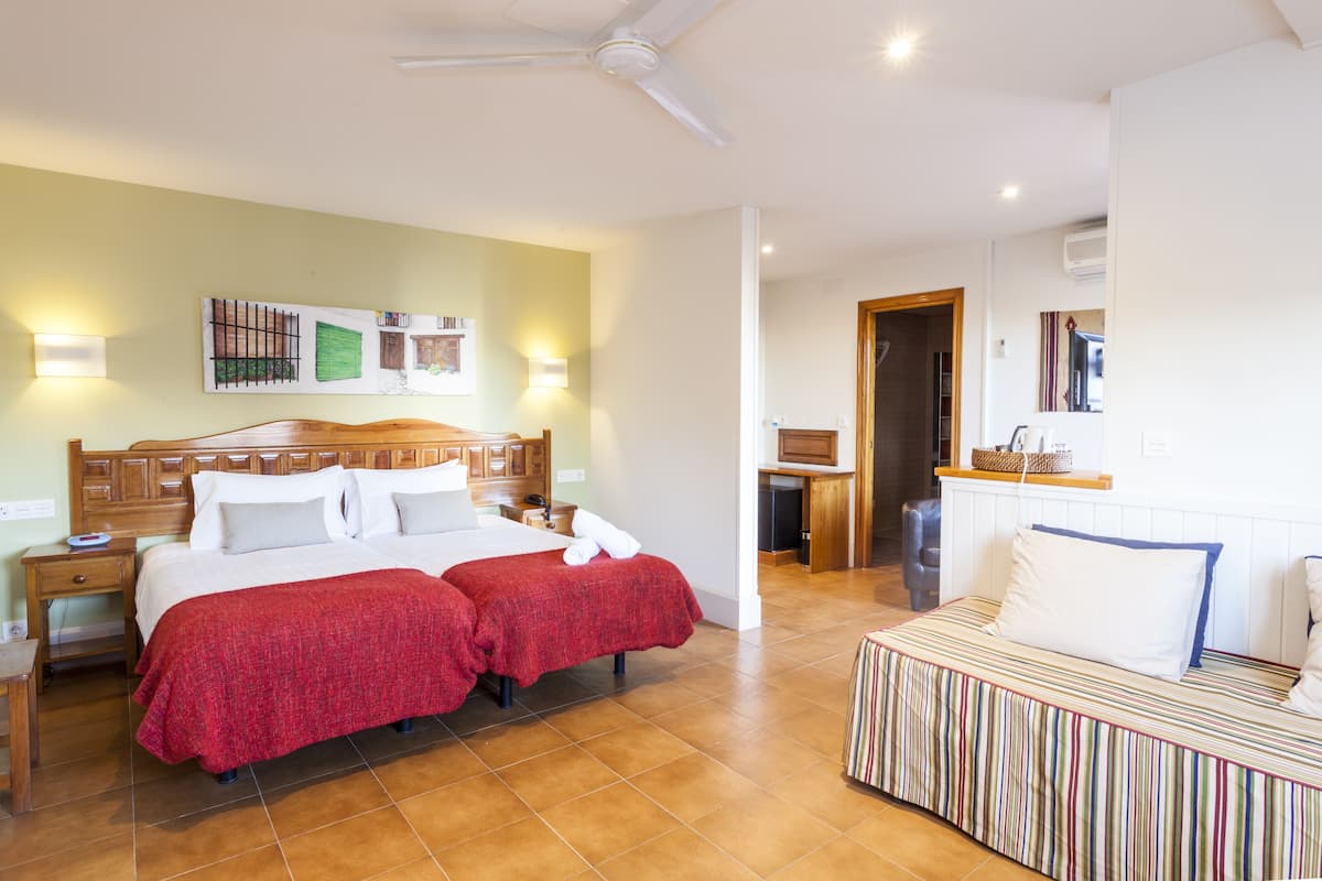 A hotel room with a large bed, a smaller bed, a desk, and a bathroom.