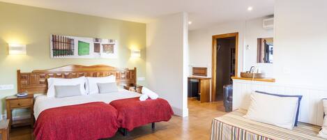 Una habitación de hotel con una cama grande, otra más pequeña, un escritorio y un baño.