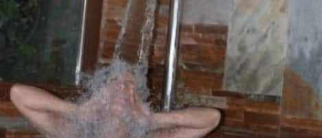 A person in a bathtub with a mirror above it.