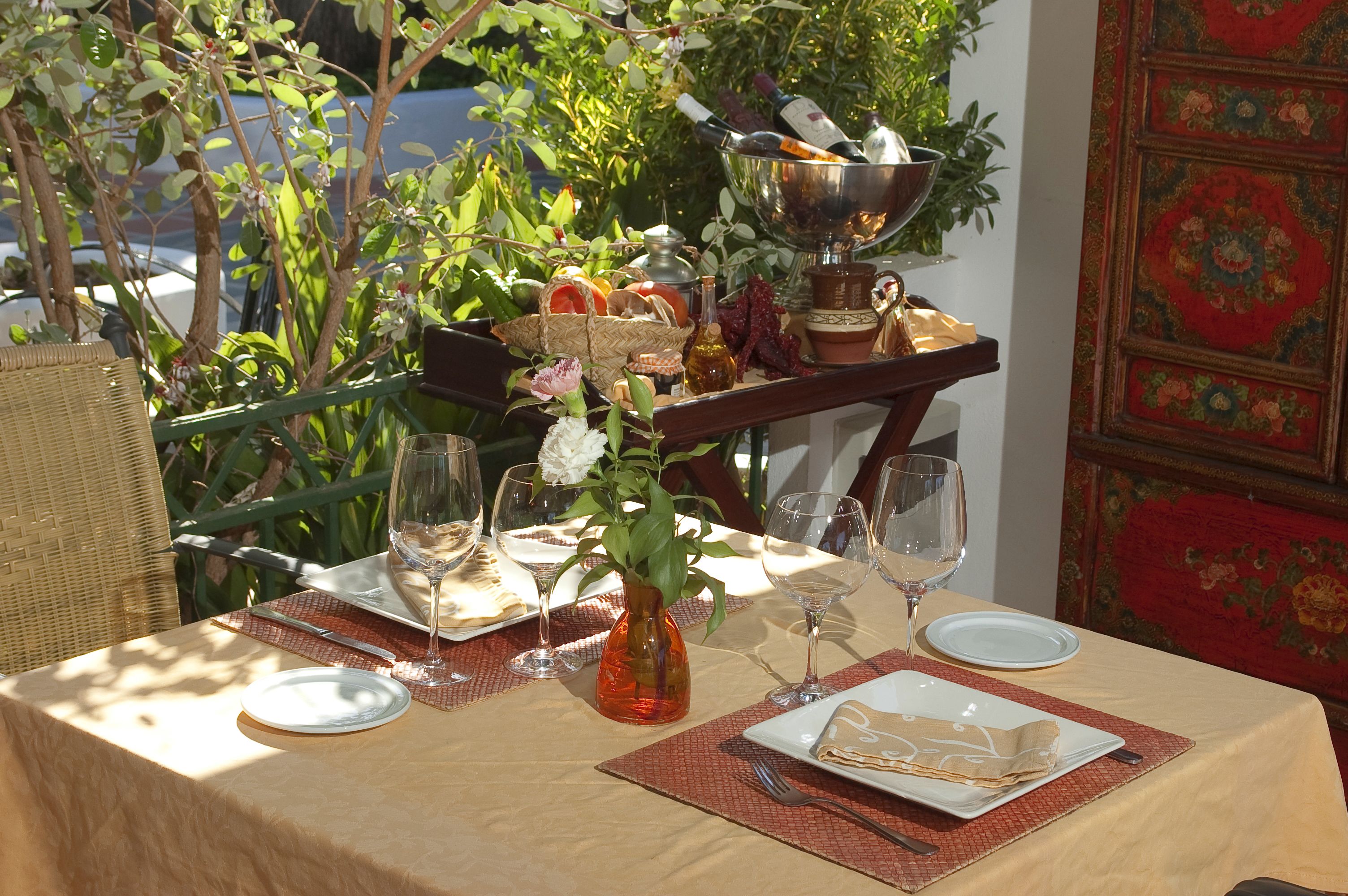 Una mesa preparada para una comida, con un florero, copas de vino y un plato de comida.