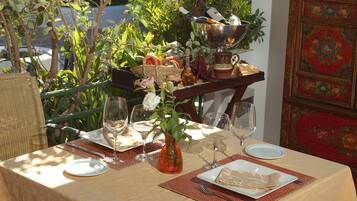 Una mesa preparada para una comida, con un florero, copas de vino y un plato de comida.