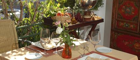 Una mesa preparada para una comida, con un florero, copas de vino y un plato de comida.