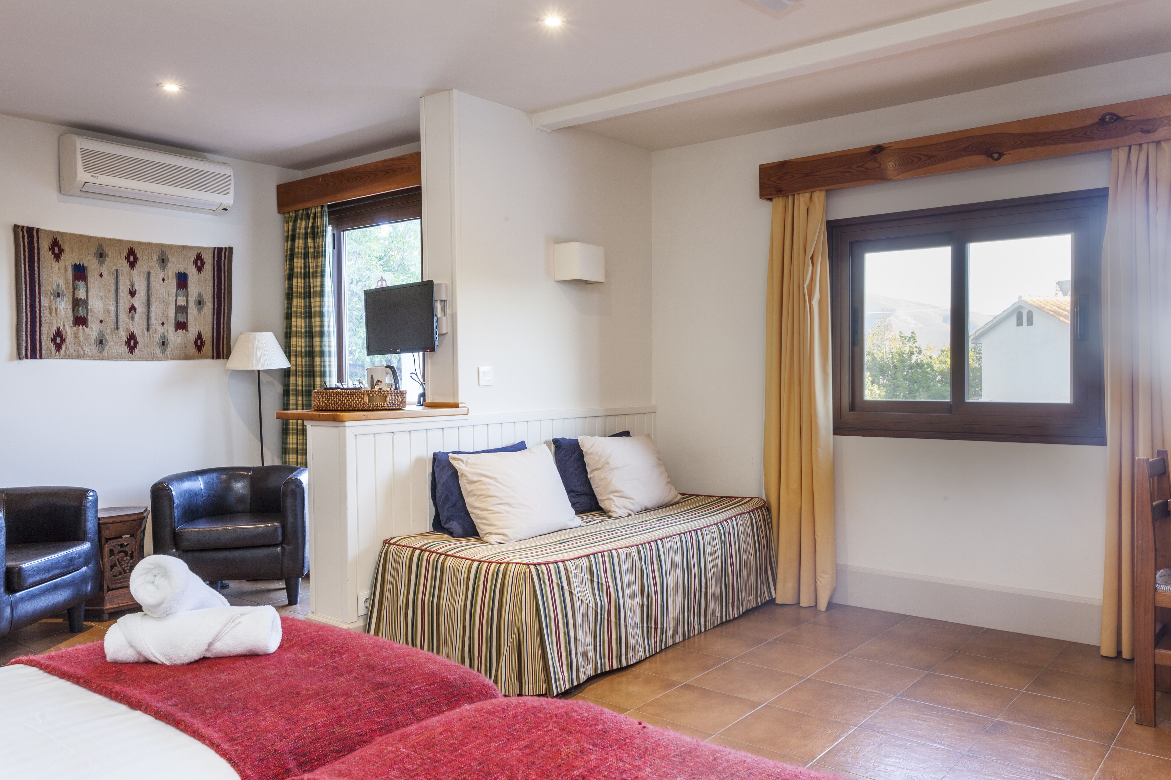 A hotel room with a bed, a chair, a TV, and a window with curtains.